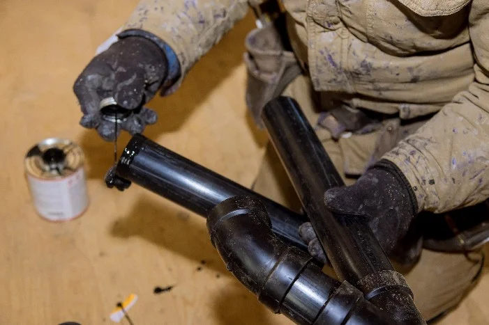 Person verklebt Abflussrohre.